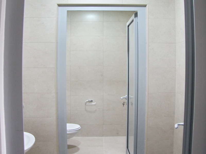 Modern bathroom in an office in Budva, Montenegro: light tiles, high-quality plumbing, and stylish finishes.