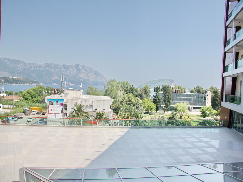 View from the spacious terrace of an office center in Budva, Montenegro: a panorama of the sea, mountains, and a green park.
