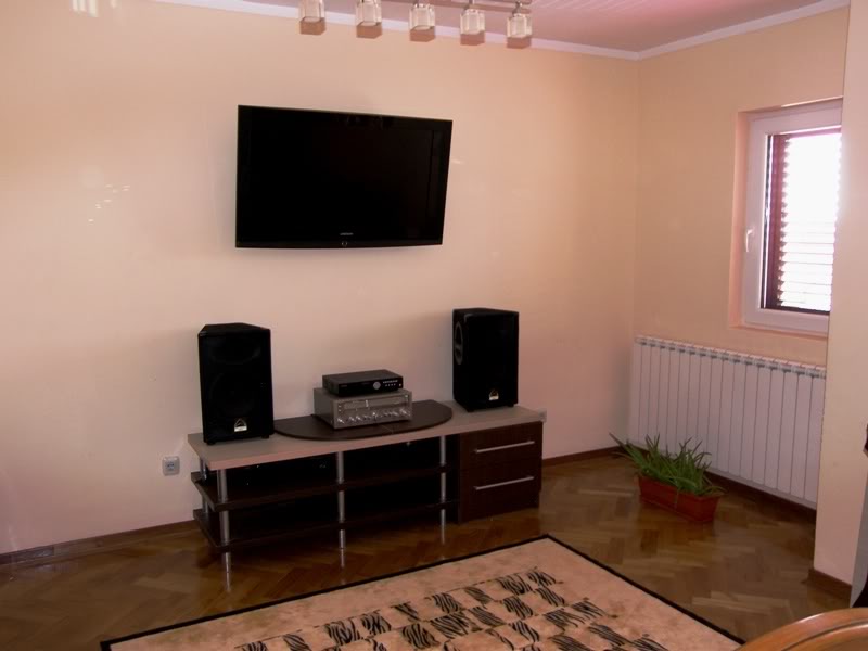 Living room in a house in Budva, Montenegro: TV area with a cabinet, audio system, parquet flooring, and a heating radiator.