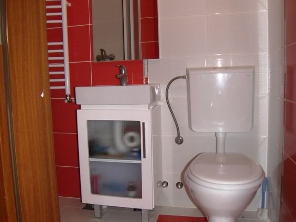 Bathroom in a house in Budva, Montenegro: white fixtures, a vanity with sink, and red tile wall finish.