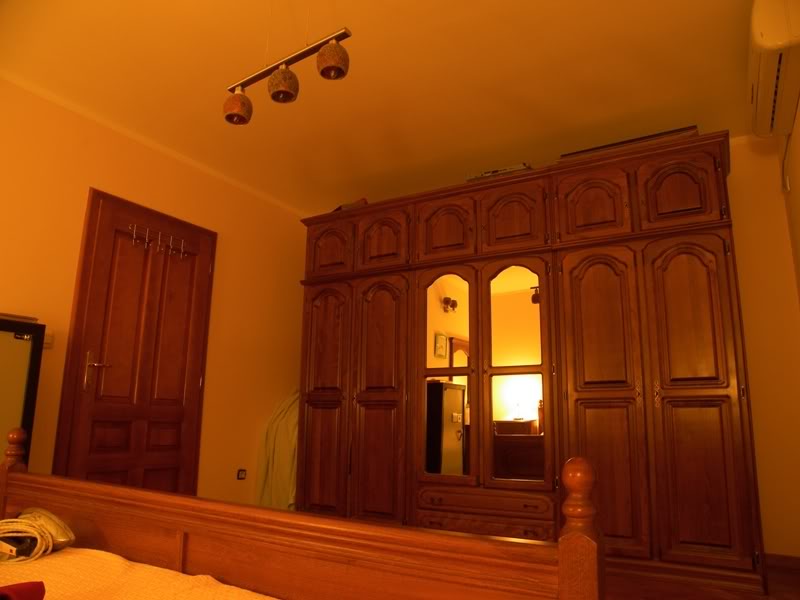 Bedroom in a house in Budva, Montenegro: a classic wooden wardrobe with a mirror, a double bed, and cozy lighting.