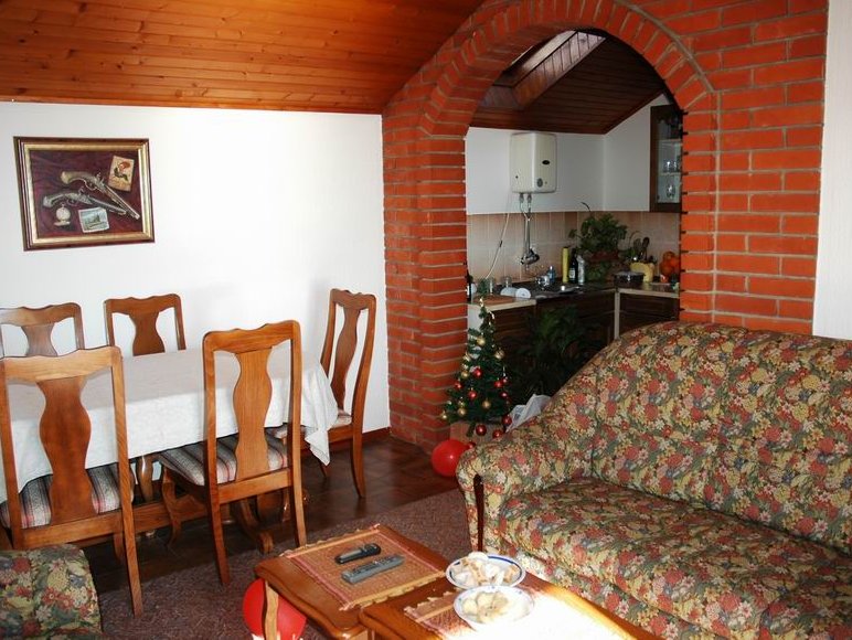 Living room in a house in Herceg Novi, Montenegro: brick arch, wooden ceiling, dining area, and a soft sofa.
