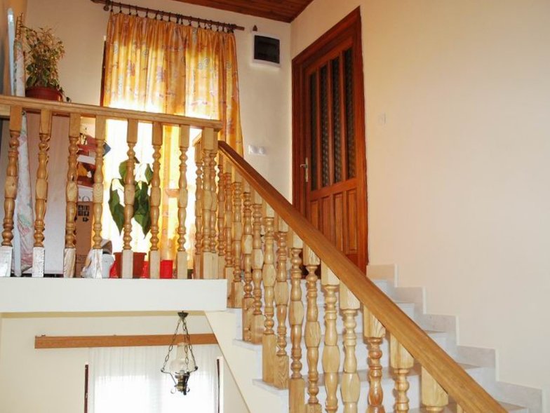 Wooden staircase with balusters in a house interior in Herceg Novi, Montenegro, with a solid wood interior door.