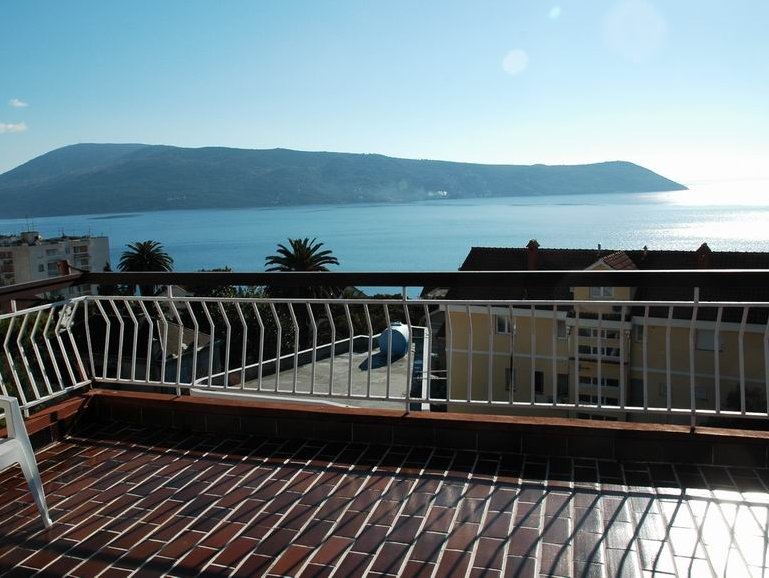 View from the house terrace in Herceg Novi, Montenegro: a panorama of the Adriatic Sea, mountains, and the tiled balcony floor.