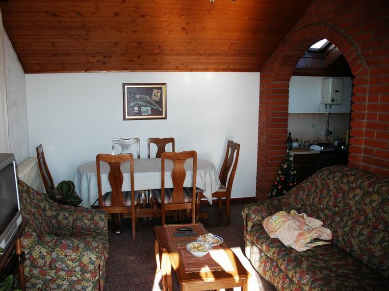 Living room with dining area in a house in Herceg Novi, Montenegro: wooden ceiling, brick arch, and upholstered furniture.