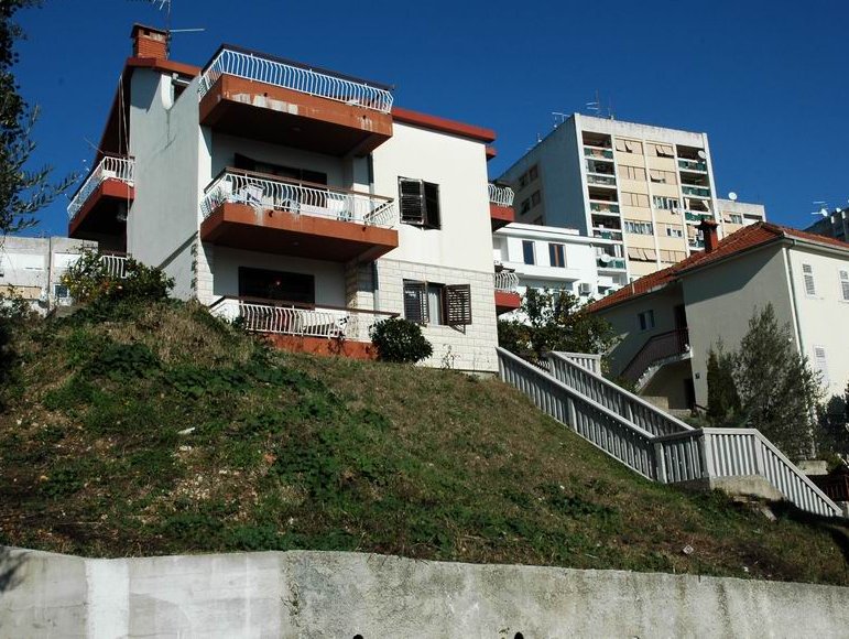 Three-story residential house with balconies and stairs on a hill in Herceg Novi, Montenegro.