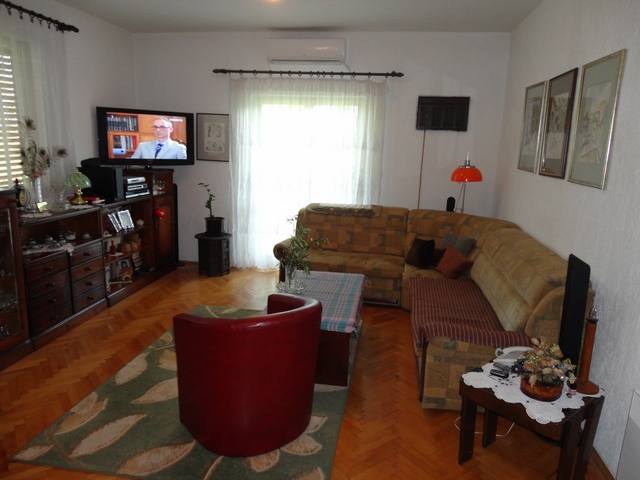 Cozy living room in a house in Herceg Novi, Montenegro: corner sofa, parquet flooring, air conditioner, and access to the terrace.