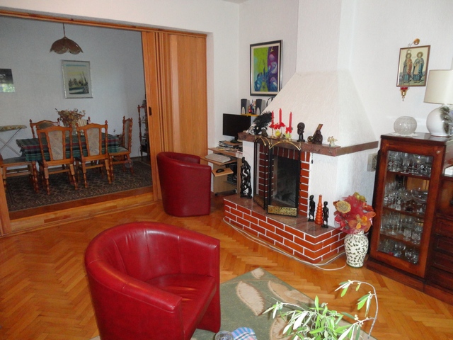 Living room with a fireplace and red armchairs in a house for sale, Herceg Novi, Montenegro: interior with dining area.
