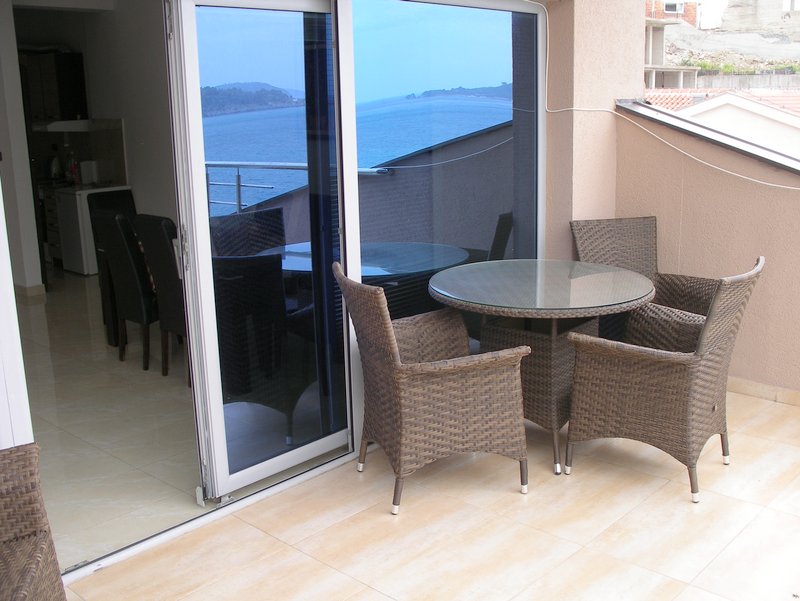 Balcony with wicker furniture and panoramic sea view in an apartment, Rafailovići, Montenegro.