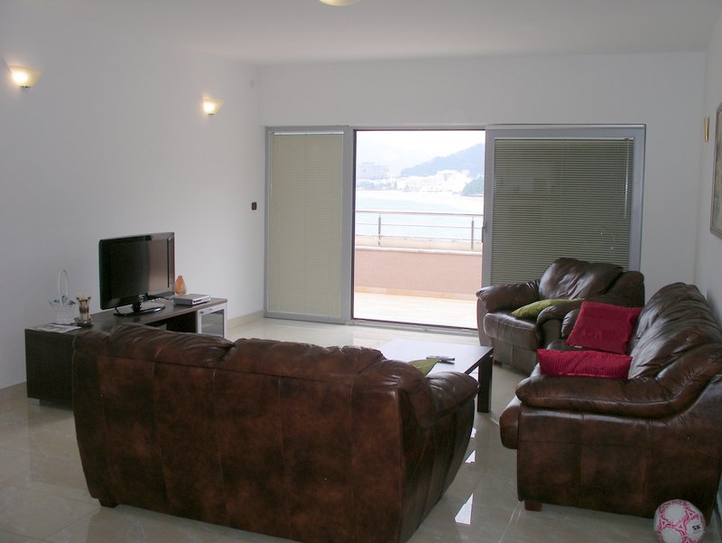 Living room with leather furniture and access to a terrace with sea view in an apartment in Rafailovici, Montenegro.