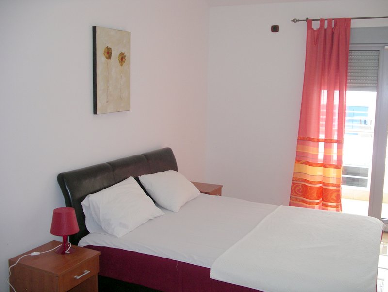 Bright bedroom with a double bed in an apartment in Rafailovici, Montenegro: balcony view and modern furniture.