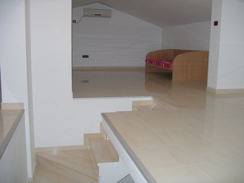 Attic living room with tile and staircase in an apartment, Rafailovici, Montenegro. Cozy seating area with a sofa and air conditioner.
