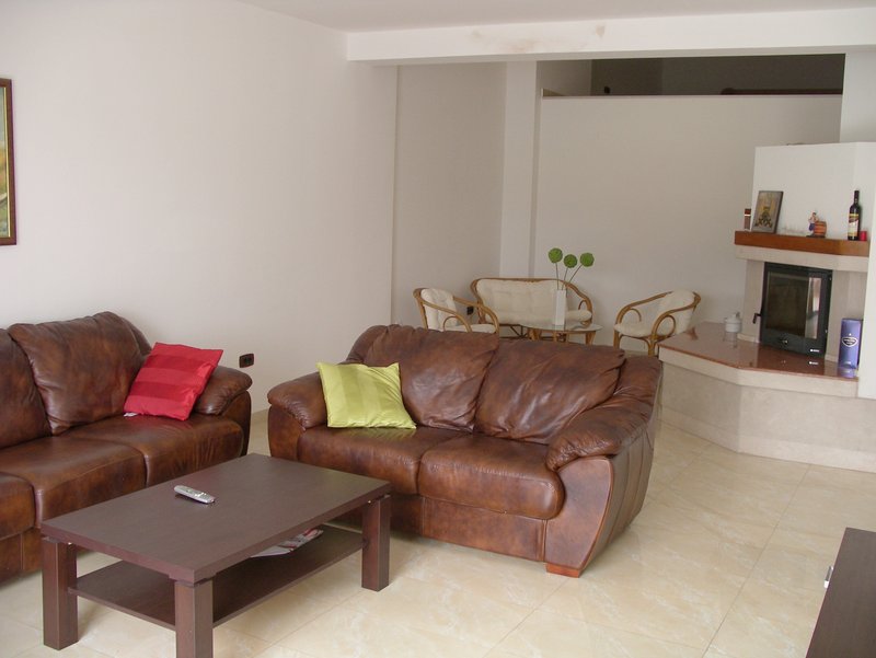 Living room in an apartment in Rafailovici, Montenegro: leather sofas, a coffee table, and a fireplace in a bright interior.