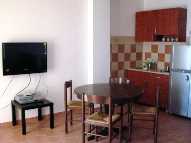 Kitchen-dining room in a villa apartment in Budva, Montenegro: dining area, wooden furniture set, and TV area.
