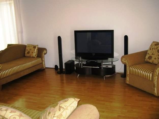 Cozy living room with soft seating and a TV area in a villa in Budva, Montenegro: bright interior, parquet flooring, and a home theater.