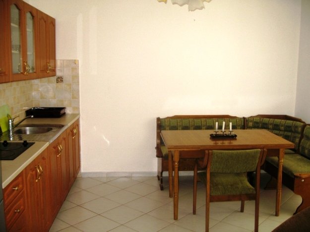 Kitchen with wooden cabinetry and dining area in a villa, Budva, Montenegro. Cozy dining room with a soft seating area.