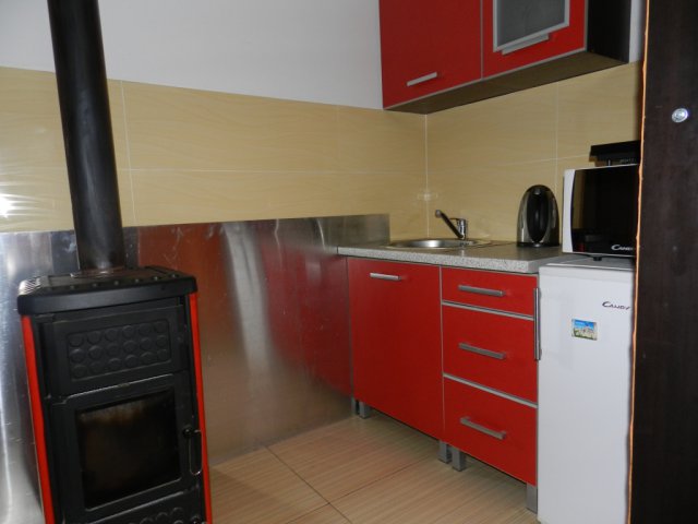 Kitchen with a red fitted set and a wood-burning stove in a house for sale, Bar, Montenegro.