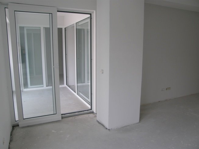Living room with panoramic windows and access to the balcony in a new apartment, Pržno, Montenegro, unfinished interior finish.