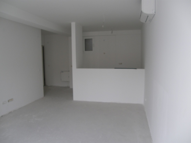 Living room in a new unfinished apartment in Pržno, Montenegro: white walls, kitchen area, and installed air conditioner.