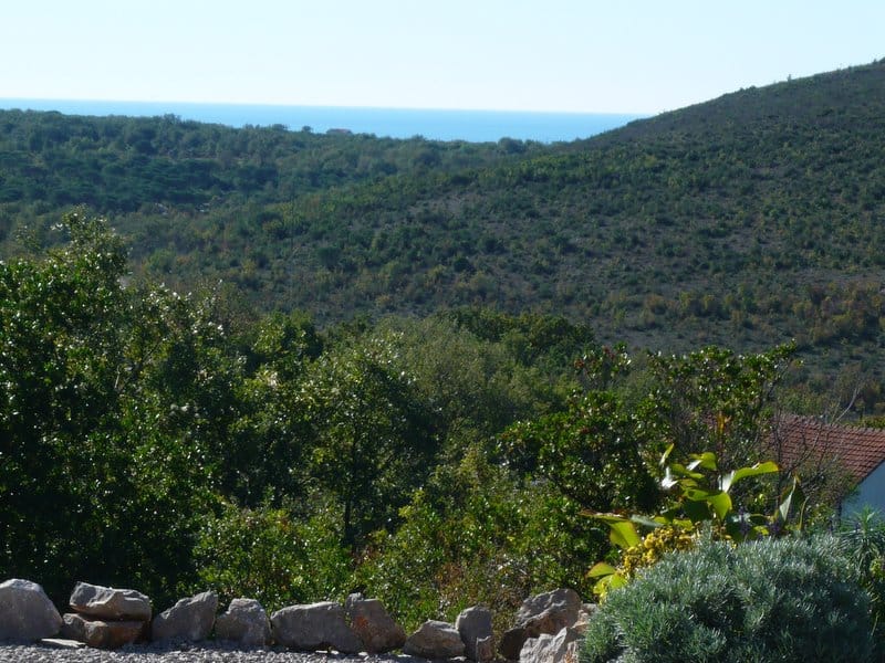 Picturesque view of green hills and the sea in the outskirts of Nikšić, Montenegro, panoramic view of the plot with a house.