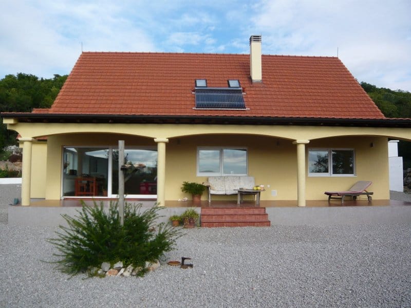 Private house in Nikšić, Montenegro: facade with a terrace, columns, a tiled roof, and solar collectors.