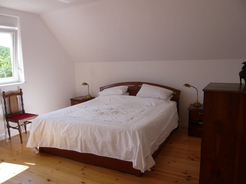 Cozy bedroom with a double bed and wooden floor in a house for sale in Nikšić, Montenegro.
