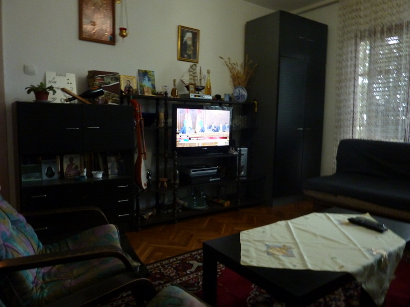 Living room with dark furniture, a TV, and a cozy seating area in a house for sale in Sutomore, Montenegro.