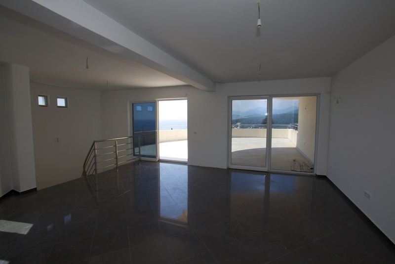 Spacious living room with panoramic windows and a terrace in a house, Uteha, Montenegro: sea and mountain views, tile flooring.