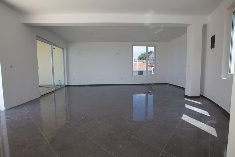 Spacious living room with porcelain tile finishes in a new building in Uteha, Montenegro, with access to the terrace.