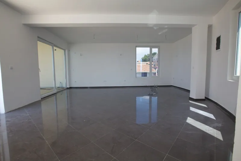 Empty room with dark glossy floor tiles, white walls, a window, and a sliding glass door leading to an exterior area.