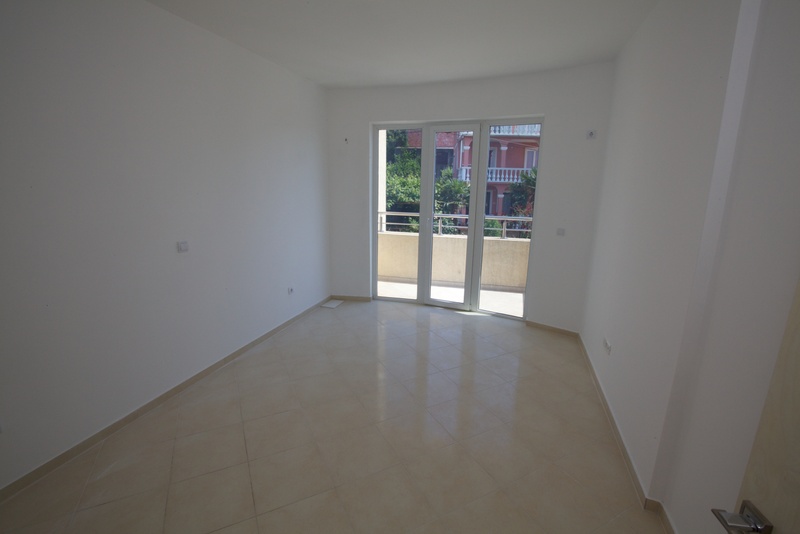 Bright empty living room with tiled floor and access to the balcony in a building, Uteha, Montenegro.