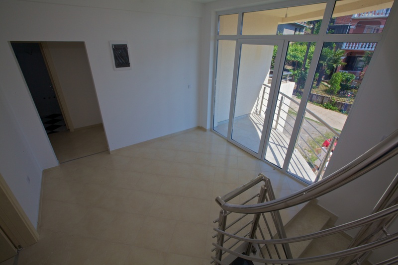 Bright living room with panoramic windows and access to the balcony in a house, Uteha, Montenegro. View of the staircase and garden.