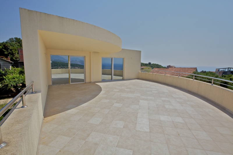 Spacious terrace with panoramic sea views in a house, Uteha, Montenegro. Light tiles and modern railings.
