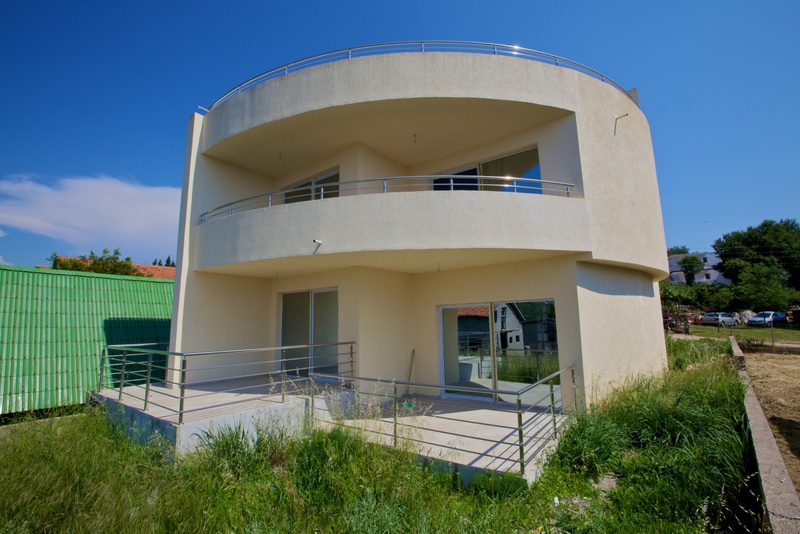 Modern two-story house with terraces and panoramic windows in Uteha, Montenegro. Round-shaped building facade.