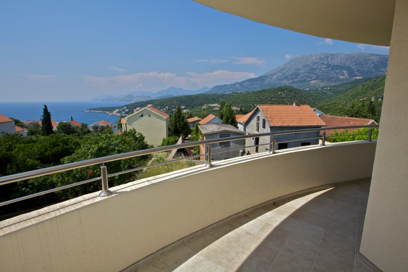 Balcony with panoramic sea and mountain views in a building, Uteha, Montenegro: tiled floor and metal railings.