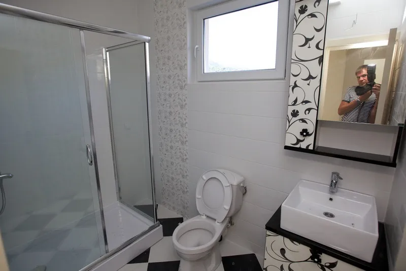 Bathroom featuring a glass shower enclosure, white toilet, and vessel sink on a patterned vanity. Black and white checkered floor.