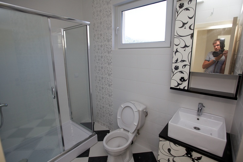 Bathroom in a house, Uteha, Montenegro: shower cabin, vanity with sink, and black-and-white tile.