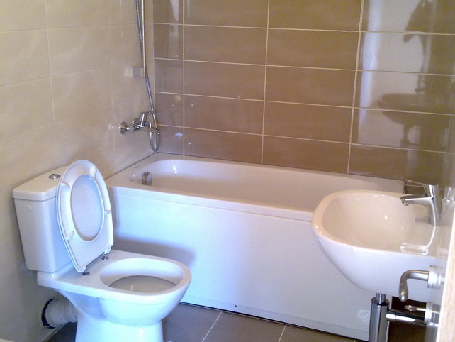 Modern bathroom with white fixtures and beige tiles in an apartment for sale, Budva, Montenegro.
