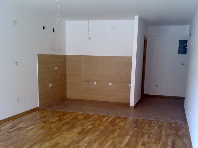 Kitchen in a new apartment in Budva, Montenegro: light finishes, tiled backsplash, and parquet flooring.