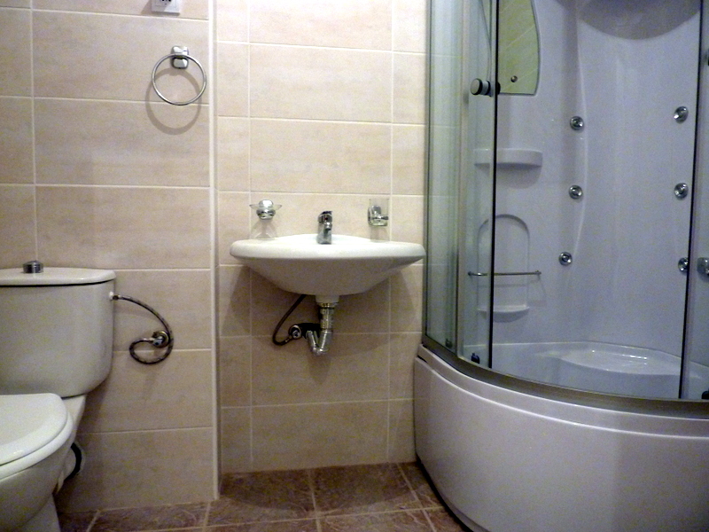 Bathroom in an apartment in Bečići, Montenegro: beige tile, a hydromassage shower cabin, and plumbing fixtures.