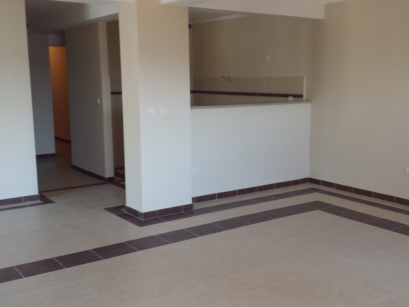 Spacious living room with tiled finishes in an apartment for sale in Pržno, Montenegro: view of the kitchen area and hallway.