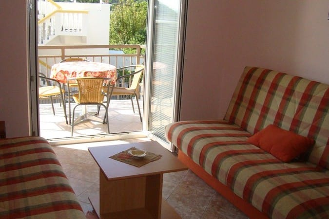 Hotel Chani living room, Montenegro: sofa, coffee table, and access to a terrace with a dining area and a view.
