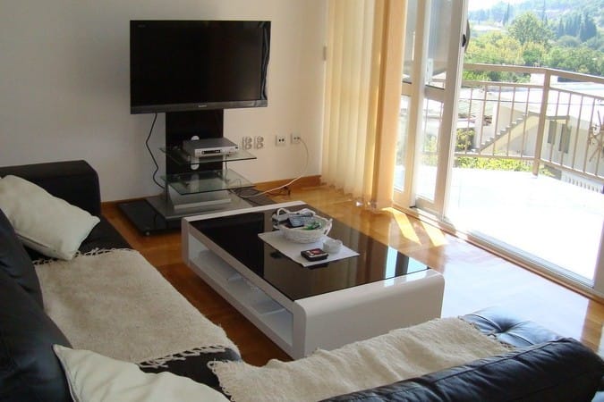 Living room with a leather sofa and access to the balcony in a hotel in Čanj, Montenegro: modern furniture and a view of nature.
