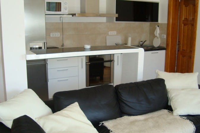 Modern studio kitchen with a bar counter and a black leather sofa in a hotel, Chan, Montenegro