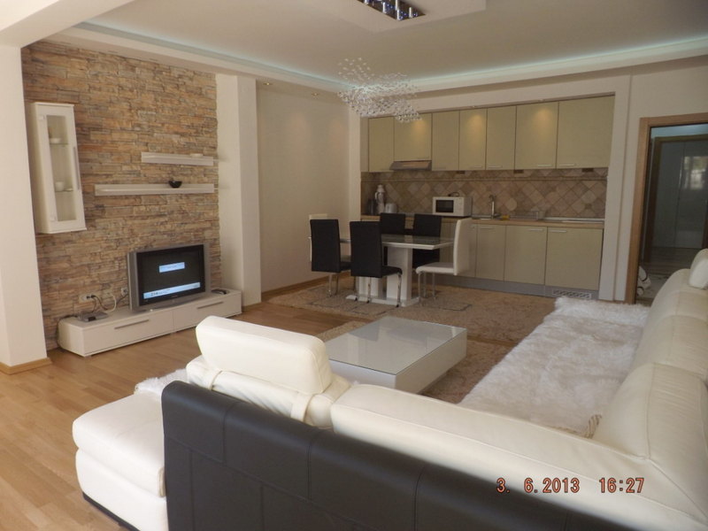 Living room with kitchen in an apartment in Pržno, Montenegro: light furniture, stone finishes, and a modern interior.