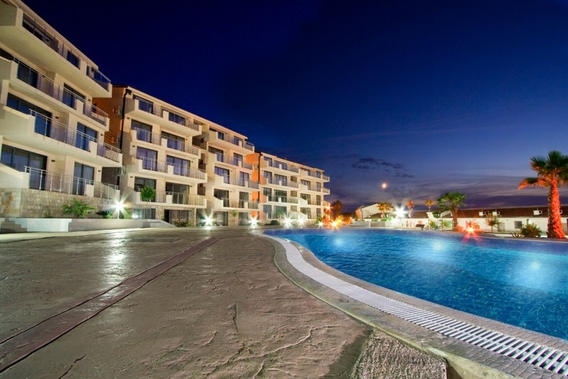 Evening view of a residential complex with a pool and terraces in Pržno, Montenegro: modern architecture and lighting.
