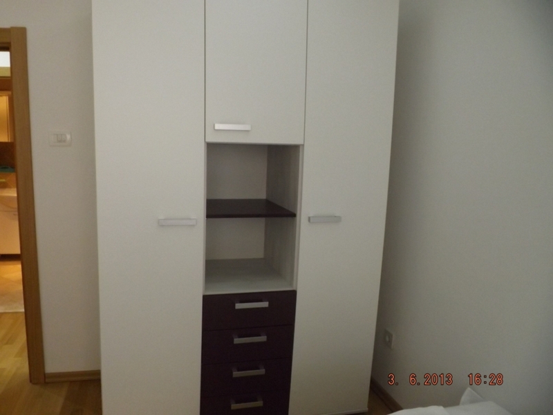 Modern white wardrobe with dark drawers in the bedroom interior of an apartment in Pržno, Montenegro.