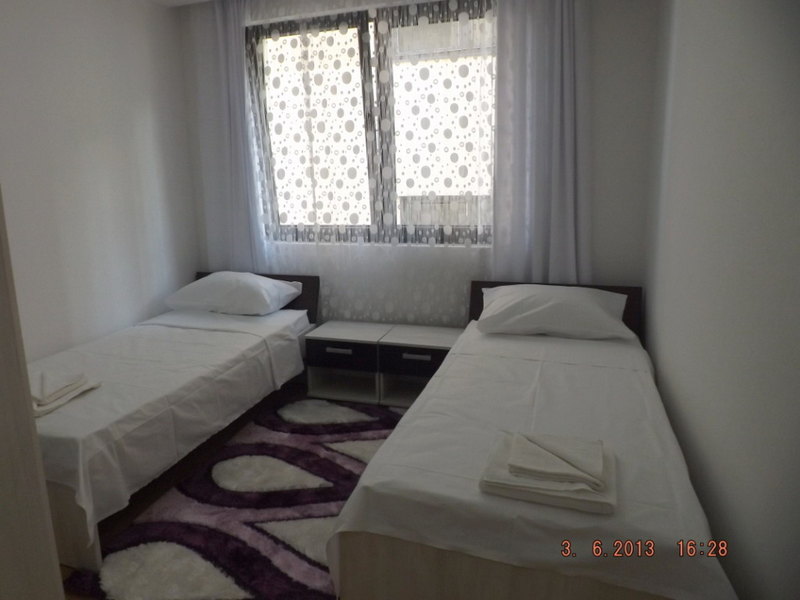 Bright bedroom with two single beds in an apartment in Pržno, Montenegro, with a rug and bedside tables.