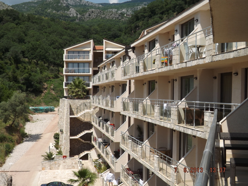 Modern residential complex with terraces in Pržno, Montenegro, against a backdrop of mountain scenery and forested area.