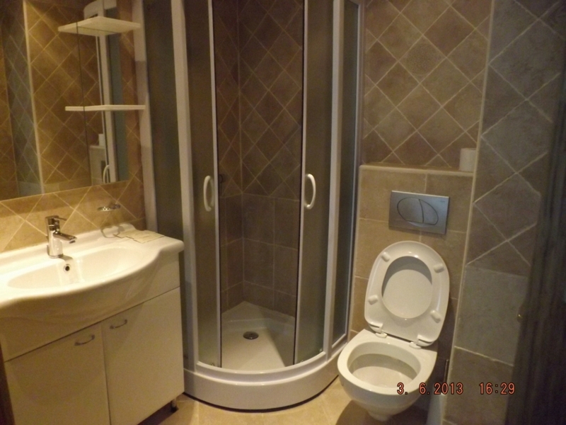 Bathroom in an apartment in Pržno, Montenegro: shower cabin, white vanity with sink, and wall-mounted toilet.